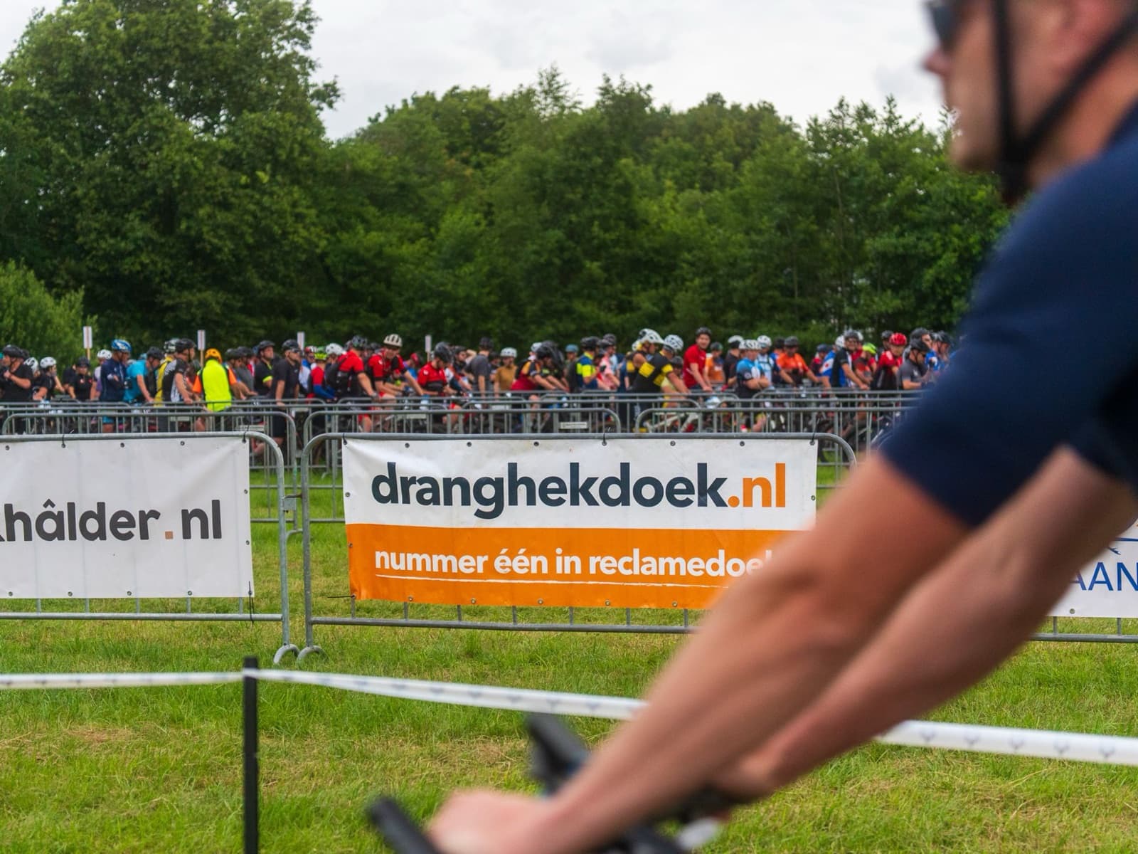 Volle startvak van De Hel van Harkema achter dranghekken met sponsordoeken